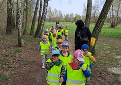 Dzieci maszerują po lesie w parach.