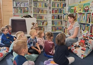 Dzieci siedzą i słuchają o pracy w bibliotece.