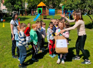Dzieci zgromadzone wokół pani dyrektor PM Nr 122- otrzymują od niej nagrodę za udział w spartakiadzie.