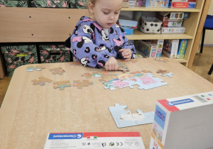 Dziewczynka układa puzzle.