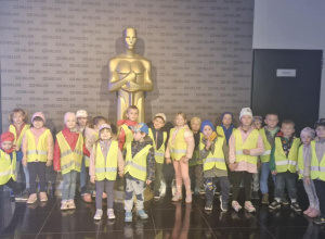 Grupowe zdjęcie dzieci przed statuetką Oscara.