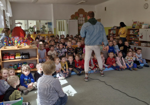 Dzieci siedzą na widowni. Pan Feliks wita się ze wszystkimi przedszkolakami.