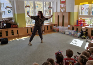 Dzieci siedzą na widowni i oglądają pokaz tańca hiphopowego.