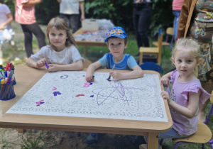 Czy zmalujemy coś razem? Dzieci kolorują kredkami duże kolorowanki.