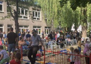 Cała społeczność przedszkola bawi się na rodzinnym pikniku w ogrodzie.