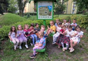 Dzieci siedzą na ławce w czarodziejskim ogrodzie.