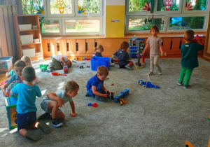 Dzieci bawią się na dywanie wybranymi przez siebie zabawkami.