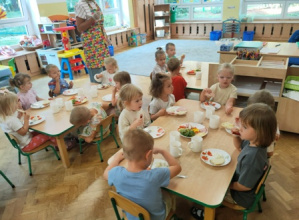 Dzieci siedzą przy stolikach, czekają na rozpoczęcie śniadania.