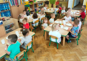 Dzieci usiadły przy stolikach, czekają na rozpoczęcie śniadania.