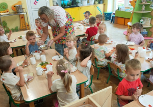 Ciocia zachęca dzieci do skosztowania miodu.