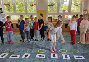 Dzieci wykonują zadanie ruchowe - skaczą po obręczach zgodnie z kodem.
