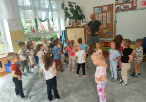 Krótka rozgrzewka przy muzyce- dzieci stoją w rozsypce na dywanie, kręcą bioderkami.