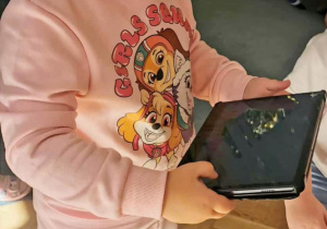 Dziewczynka wpisuje polecenia dla robota na tablecie.