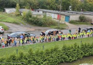 Zdjęcie z lotu ptaka. Wszystkie dzieci idą wspólnie na spacer po okolicy, aby uczcić swoje święto - Dzień Przedszkolaka.