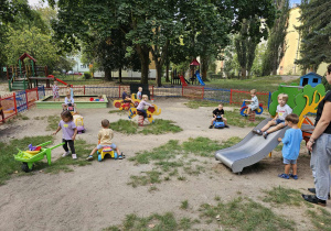Dzieci korzystają ze sprzętu terenowego na placu zabaw.