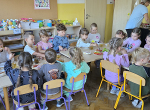Dzieci siedzą przy stole i przygotowują pyszne śniadanie.
