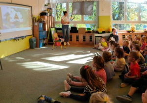 Dzieci oglądają film edukacyjny wyświetlony na tablicy multimedialnej.