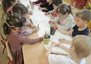 Dzieci wykionują swoją wspólna pracę plastyczną Drzewa owocowe w sadzie.