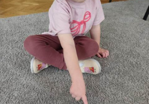 Dziewczynka wskazuje emotkę , która określa jej nastrój.