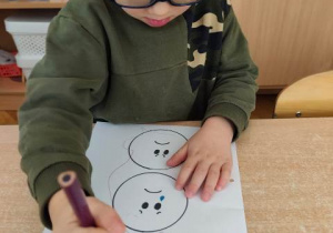 Chłopiec koloruje emotkę wybraną przez siebie- określa jak się czuje.