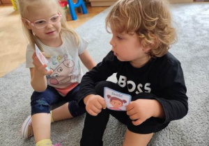 Dziewczynka pokazuje koledze wybrany przez siebie obrazek ilustrujący jej nastrój.