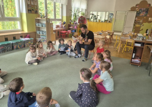 dzieci siedzą na dywanie i słuchają.