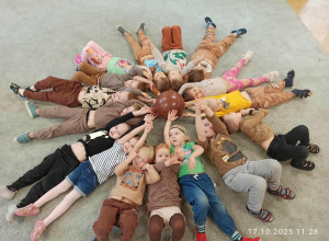 Dzieci leżą w kole, głowami skierowanymi do środka.