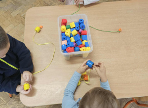 Dzieci nawlekają koraliki.