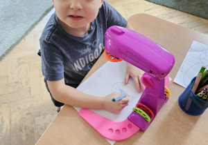 Chłopiec rysuje z wykorzystaniem projektora.