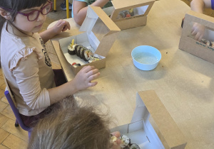 Dzieci jedzą samodzielnie przygotowane sushi.
