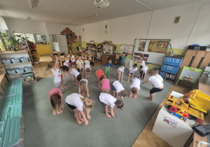 Dzieci wykonują skłony stojąc.