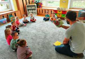Dzieci siedzą w dużym kole, słuchają bajki o strażakach.