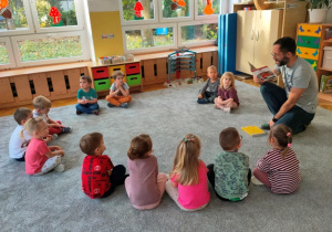 Dzieci w skupieniu słuchają opowiadania o bohaterskich strażakach.