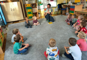 Pan Michał pokazuje dzieciom ilustracje w książce.