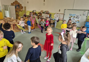 Dzieci tańczą na dywanie.