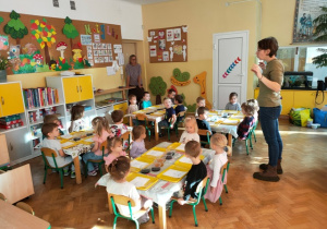 Dzieci siedzą przy stolikach na których naszykowane są materiały do ćwiczeń rączek.