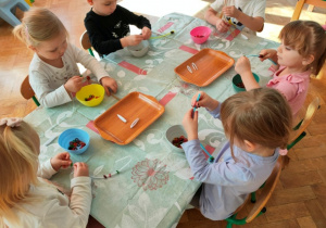 Dzieci nawlekają koraliki na druciki kreatywne.