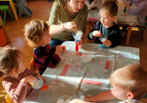 Dzieci wsypują mąkę ziemniaczaną do balonów.