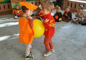 Dwaj chłopcy z najmłodszej grupy tańczą z balonem umieszczonym na wysokości ich brzuszków.