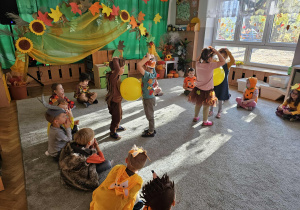 Dzieci tańczą z balonem trzymając go brzuchami.