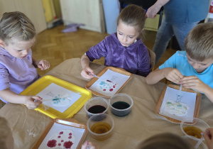Dzieci przy użyciu pipety i barwników wykonują jesienne drzewo.