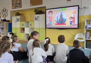 Dzieci oglądają film edukacyjny o Polsce.