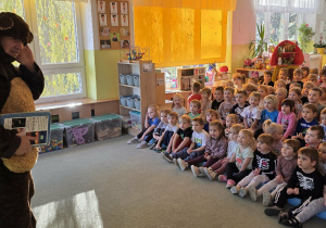 Dzieci siedzą na widowni i oglądają przedstawienie.