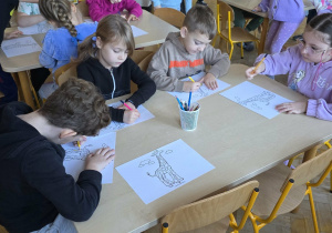 Dzieci kolorują postać żyrafy wg własnego pomysłu.