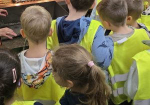 Dzieci obserwują maszynę, w której schną ozdoby choinkowe po nadaniu im srebrnego koloru.