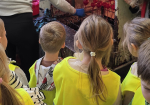 Dzieci obserwują schnięcie pomalowanych bombek w specjalnej maszynie.