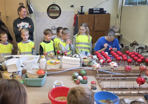 Dzieci obserwują pracę pań odpowiedzialnych za dekorowanie ozdób choinkowy.