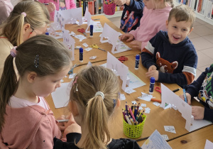 Dzieci pracują przy stolikach - wykonują świąteczne kartki z efektem 3D Pop-up.