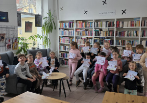 Pamiątkowe zdjęcie grupowe dzieci z samodzielnie wykonanymi pracami.