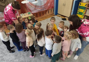 Dzieci żegnają się z trenerami okrzykiem pływackim. Ręce dzieci tworzące gwiazdę ułożone są na dłoniach trenerów.